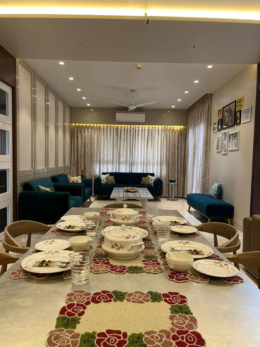 The Kogta House - dining table set for a family meal, living room beyond